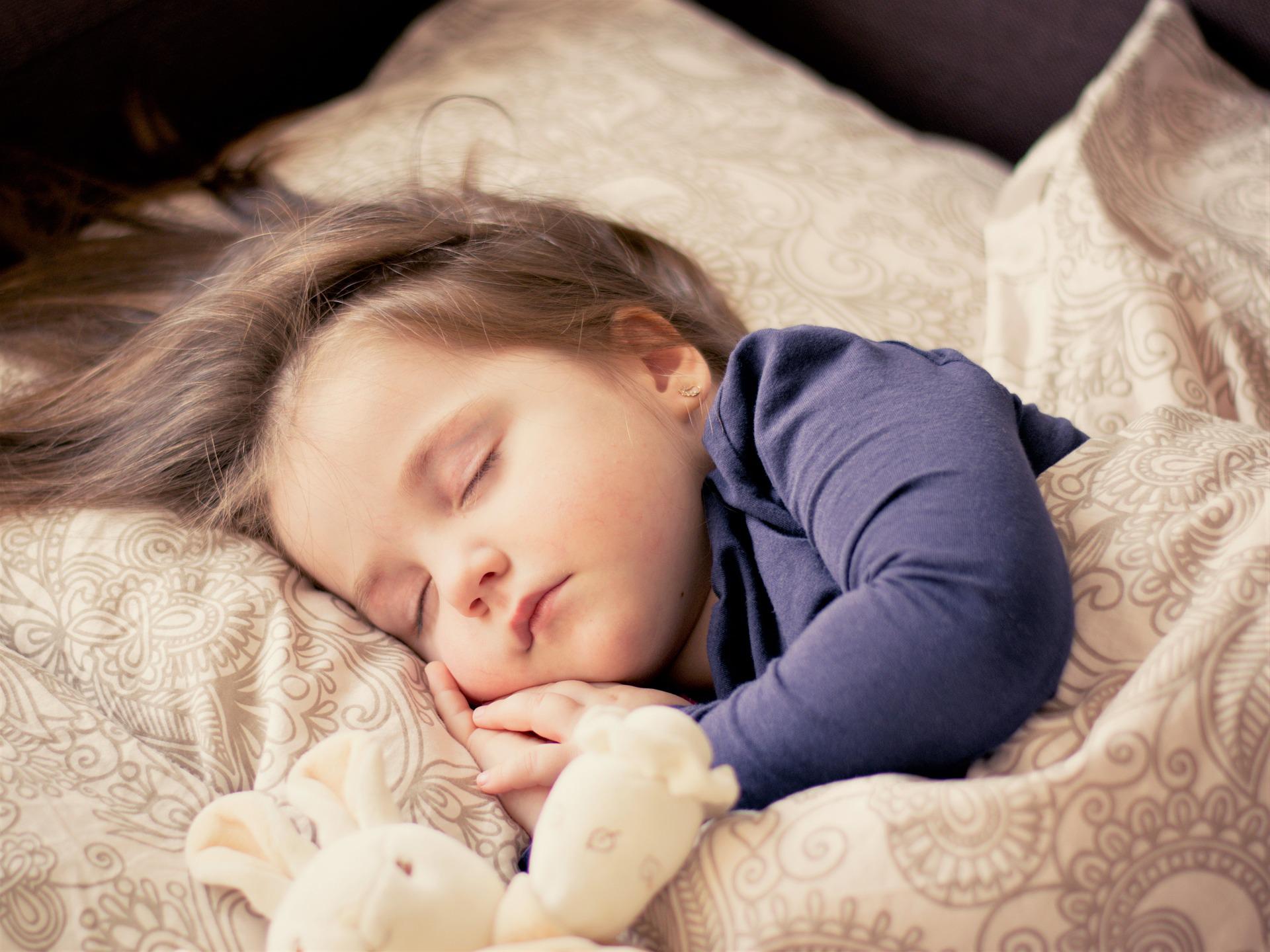 Child sleeping peacefully in bed with bunny